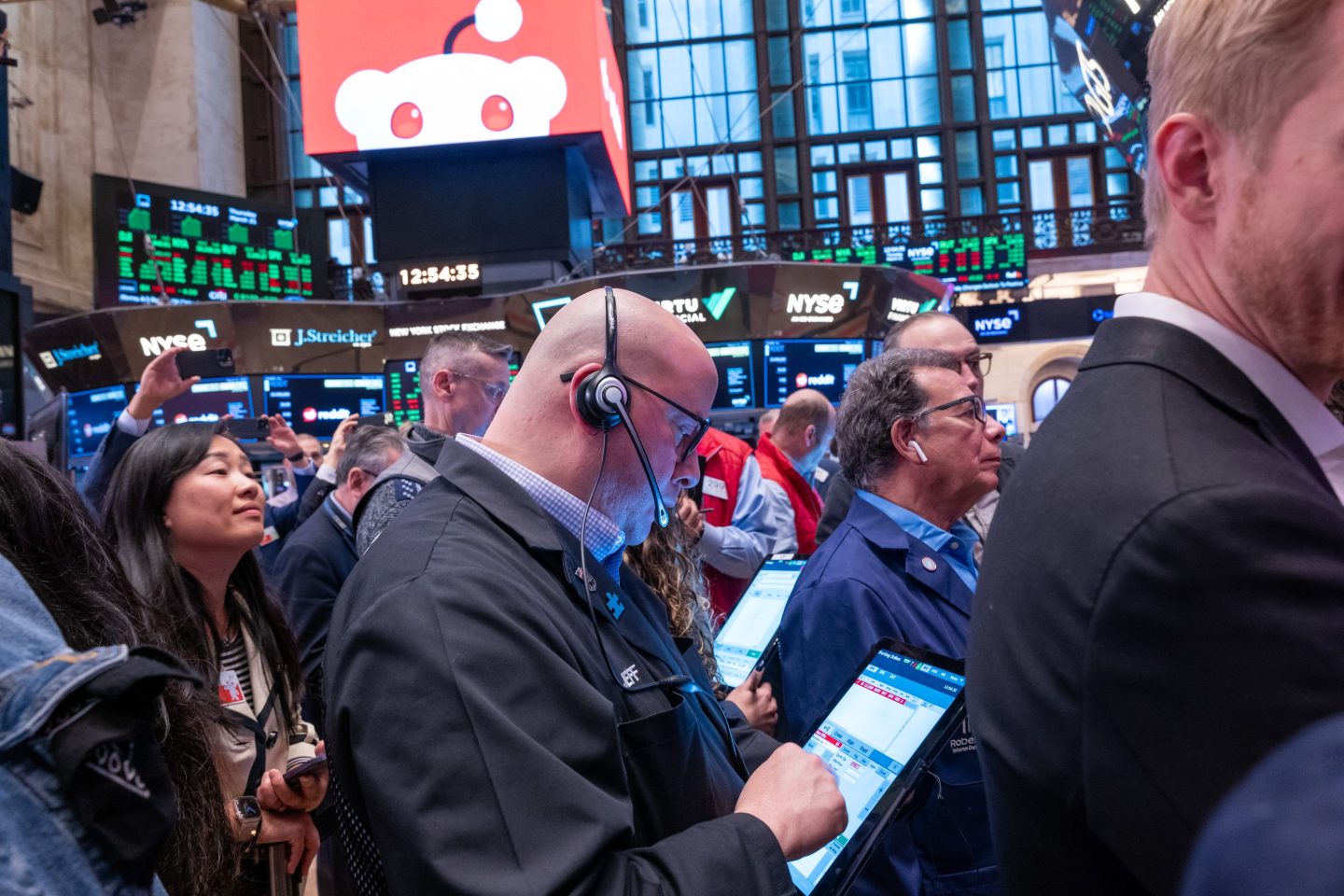 people gathered on the floor of the New York Stock Exchange monitoring screens