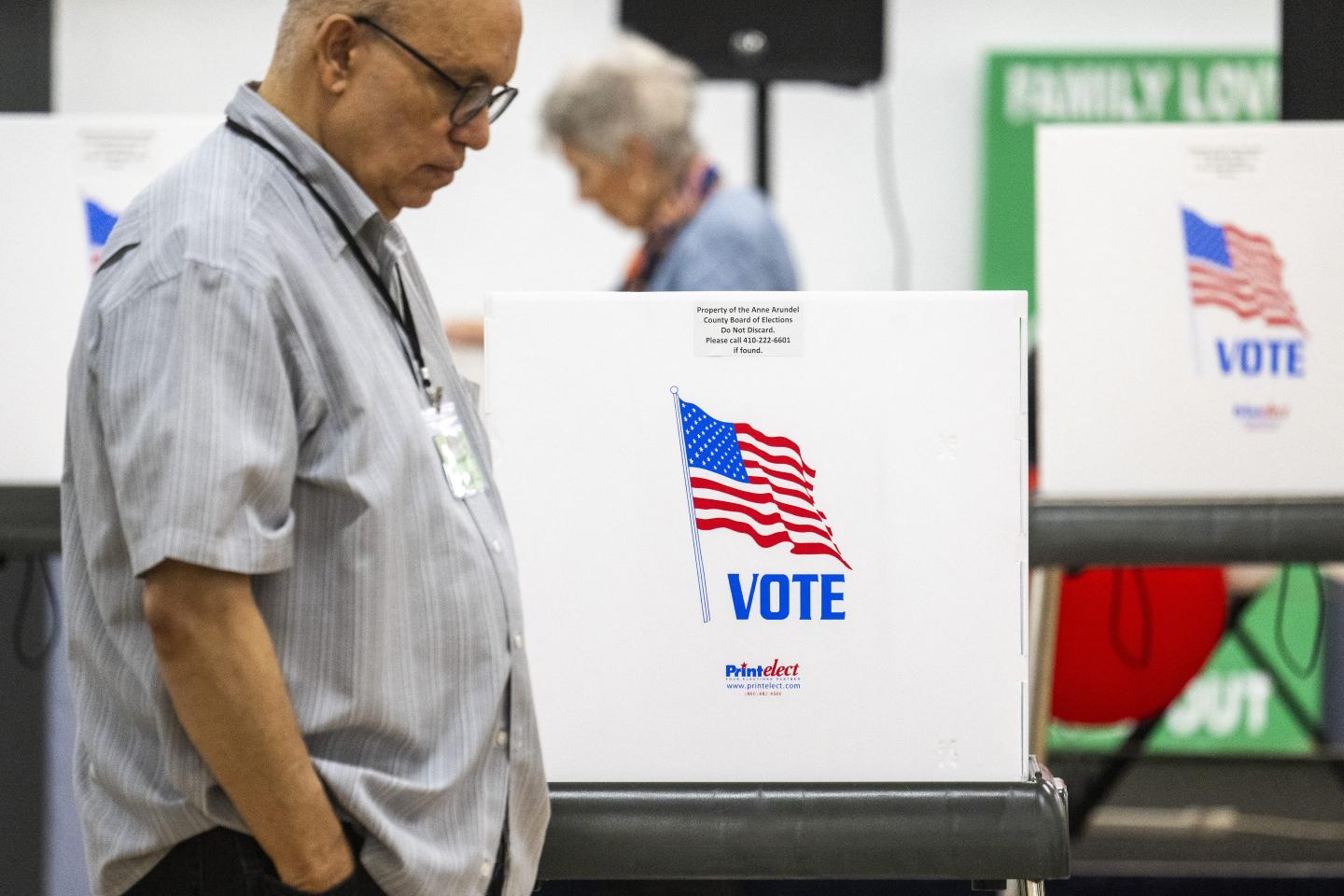 A voter at a polling place standing next to a voting booth