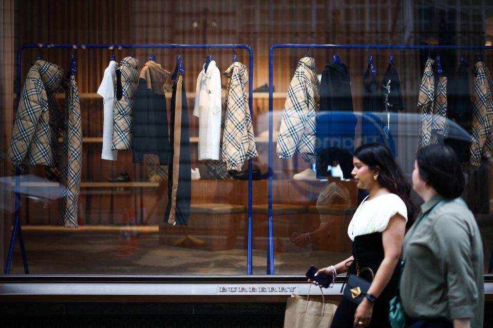 people walking past a burberry store