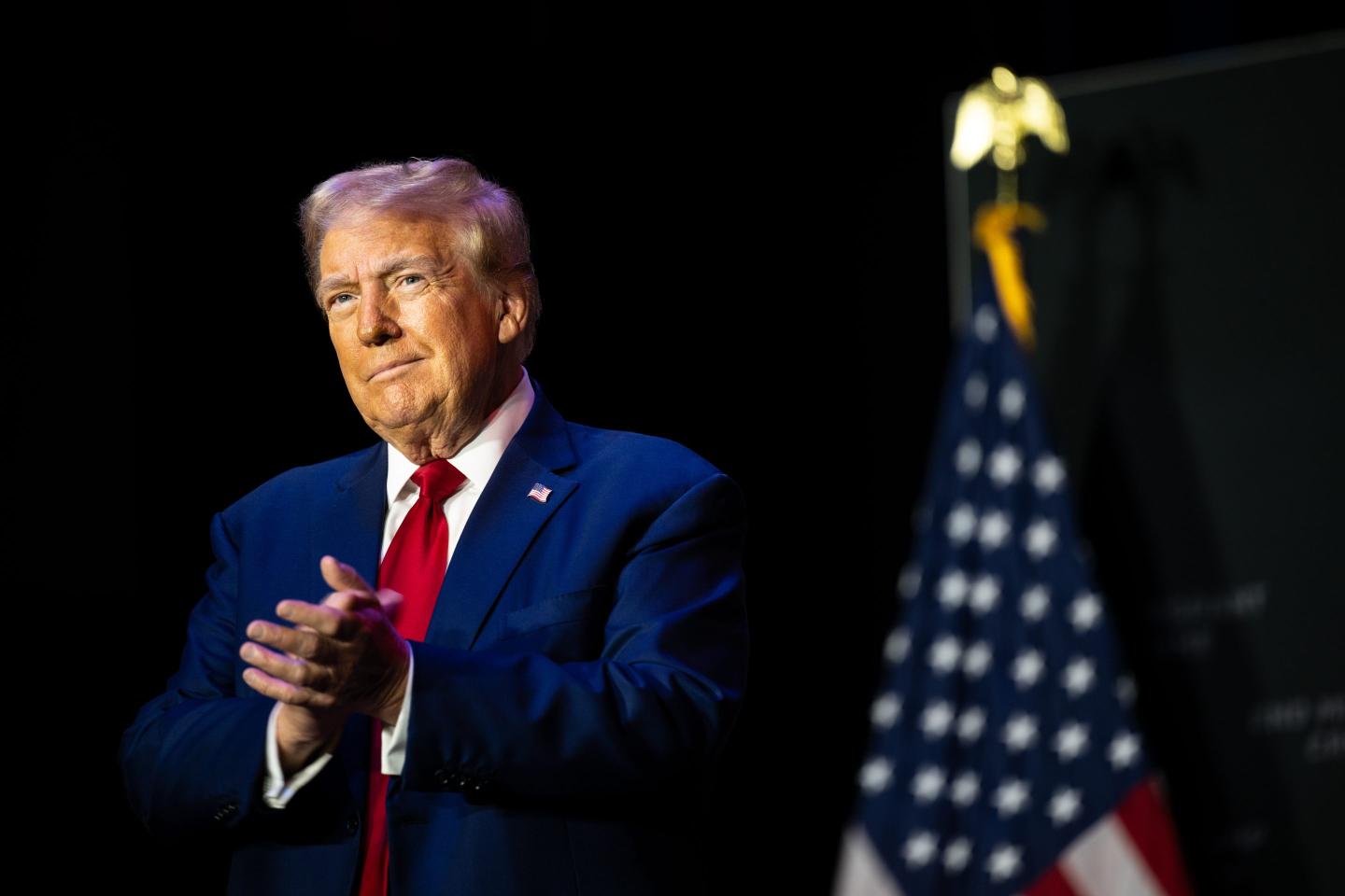 Donald Trump clapping in front of American flag