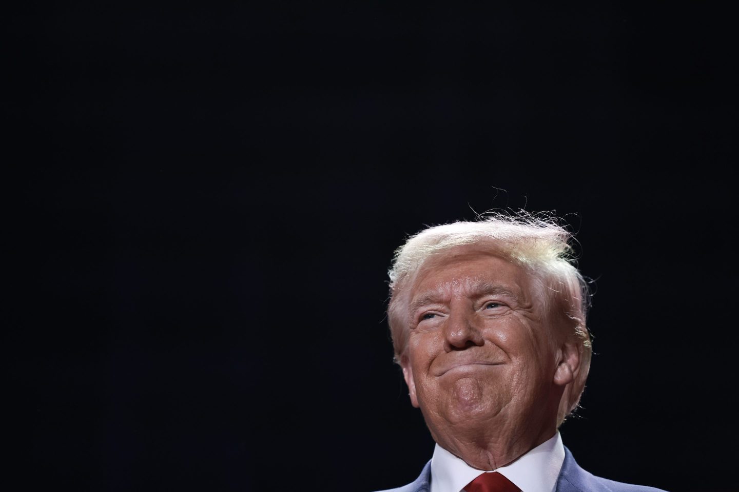Trump smiling against a black background