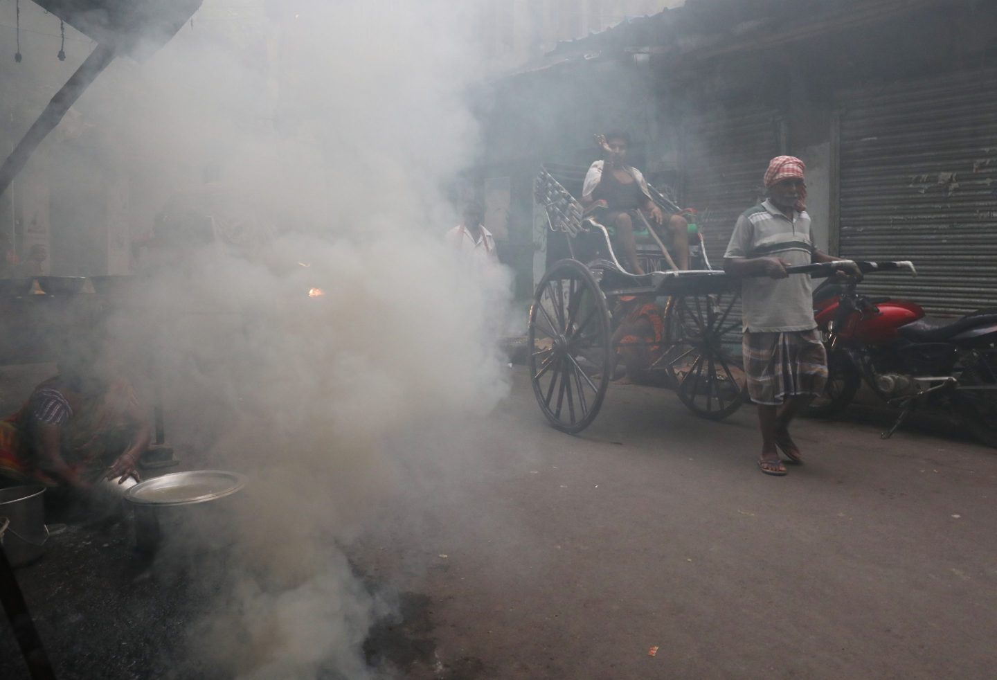 A hand-pulled rickshaw moves through thick smoke caused by the burning of coal ovens in an alley in Kolkata, India, on Oct. 28, 2024.