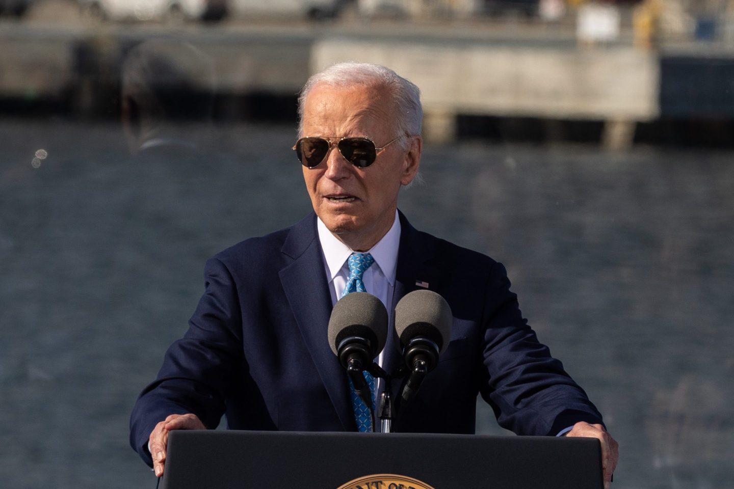 Joe Biden wearing sunglasses standing at a podium