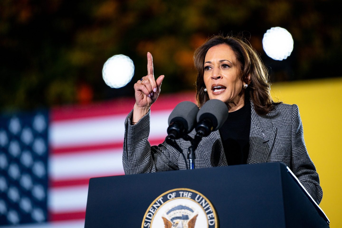Kamala Harris points up with her right hand as she speaks at a podium.