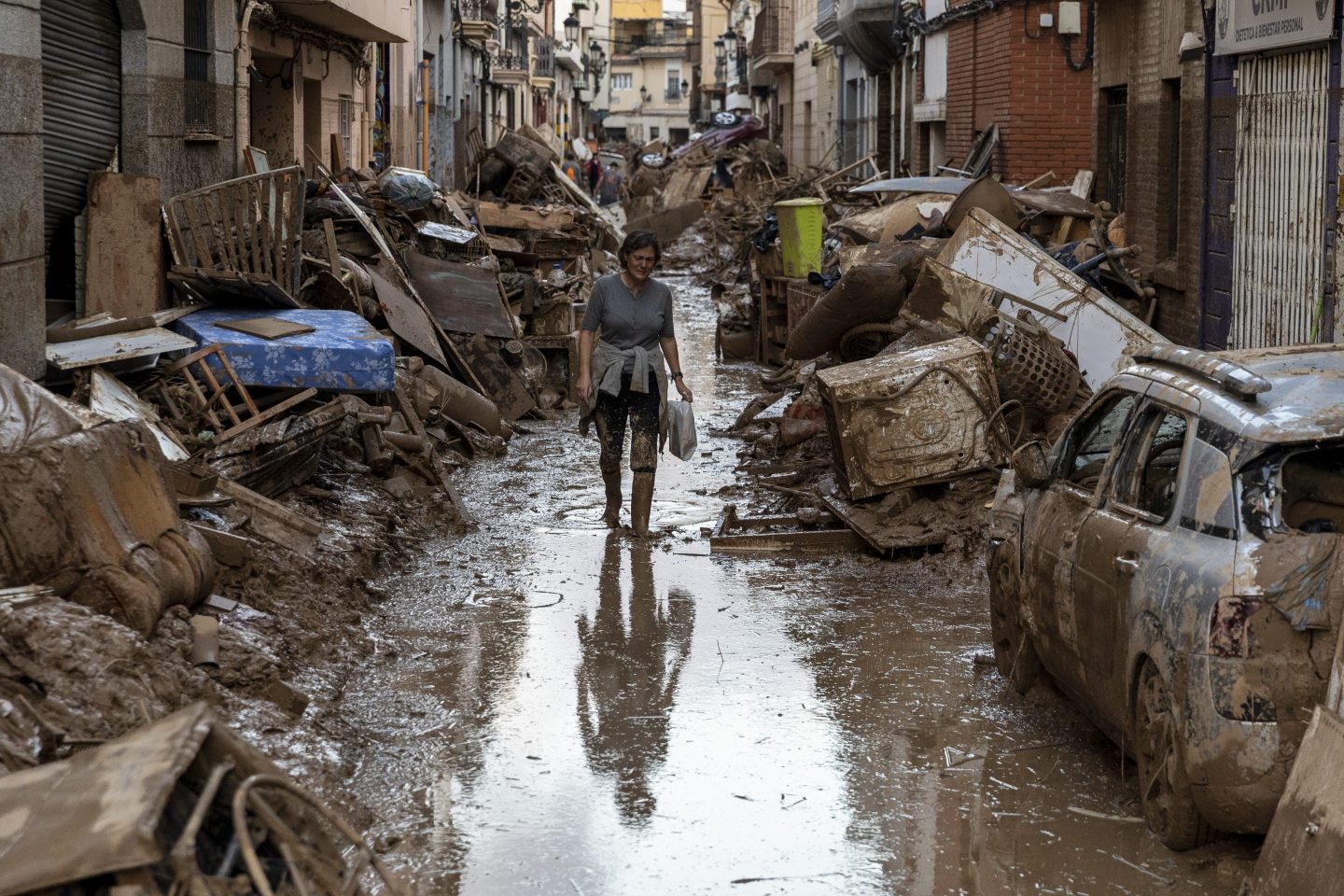A woman walks along a street full of mud and waste in Valencia, Spain, on Saturday.