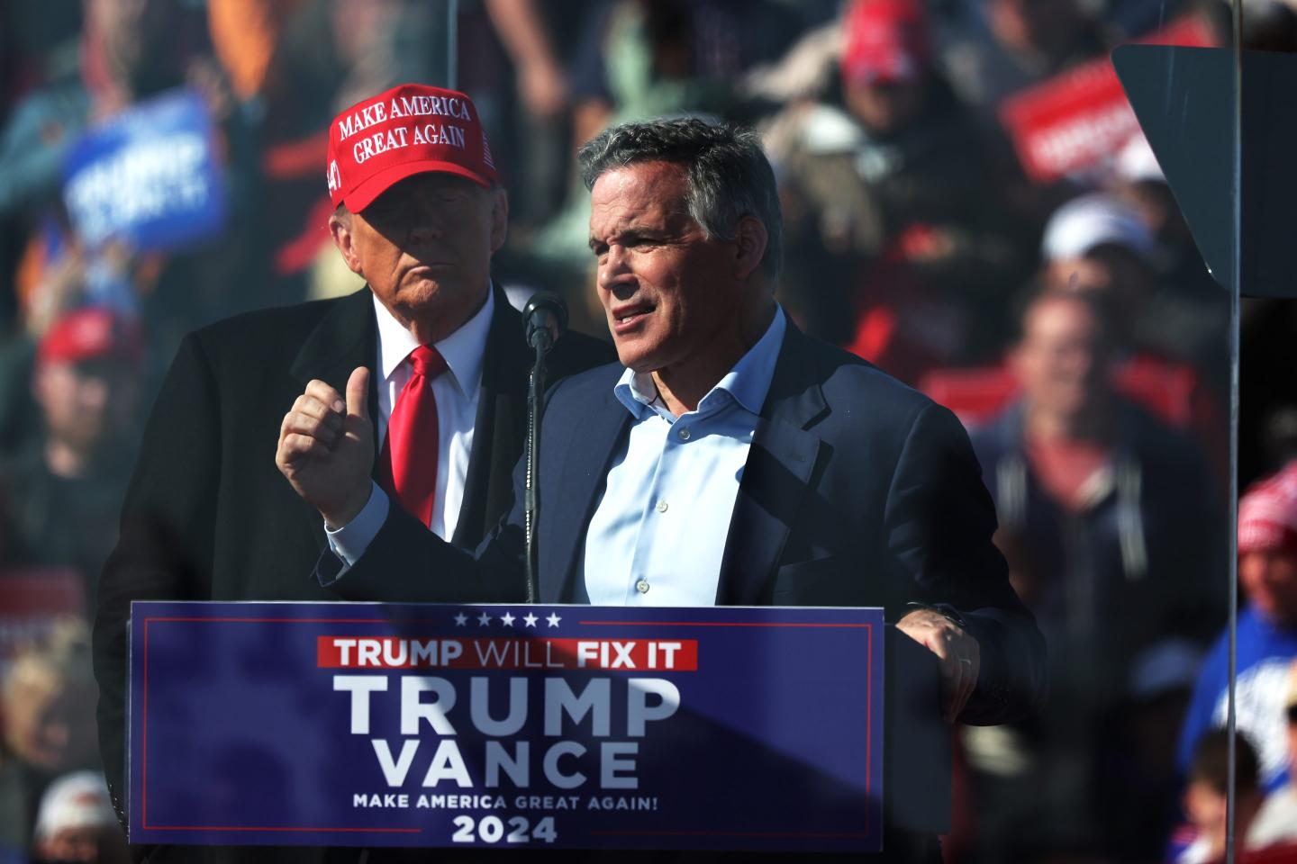 Republican Senate candidate Dave McCormick speaks while Donald Trump stands behind him.