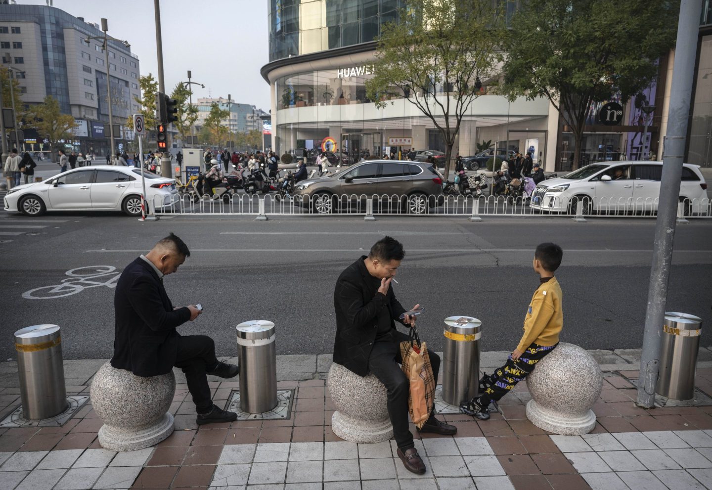 Men looking at their mobile phones as they sit in a popular shopping area in Beijing on Nov. 8, 2024.