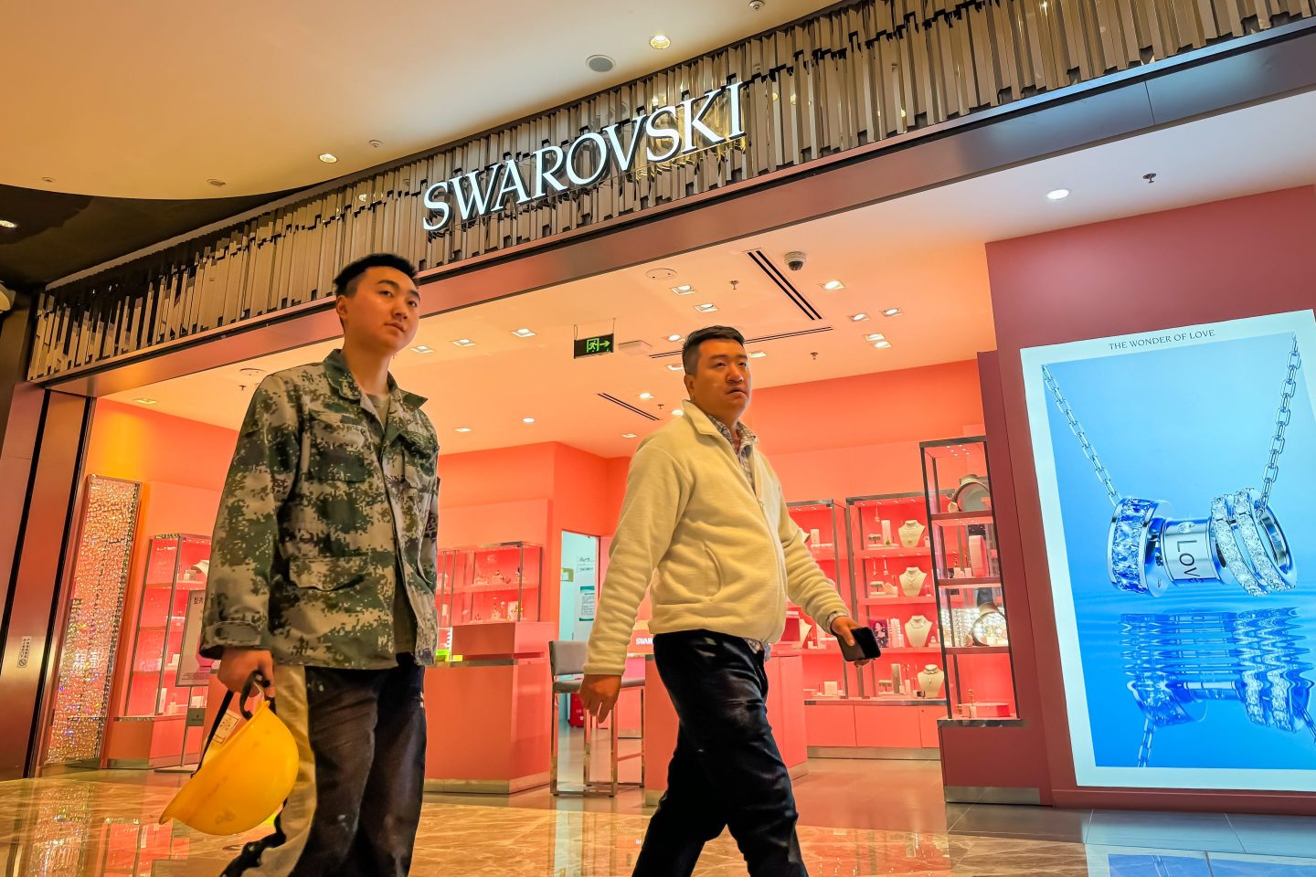 Two men walk past a Swarovski store in a shopping mall in Chongqing, China on Nov. 13, 2024.