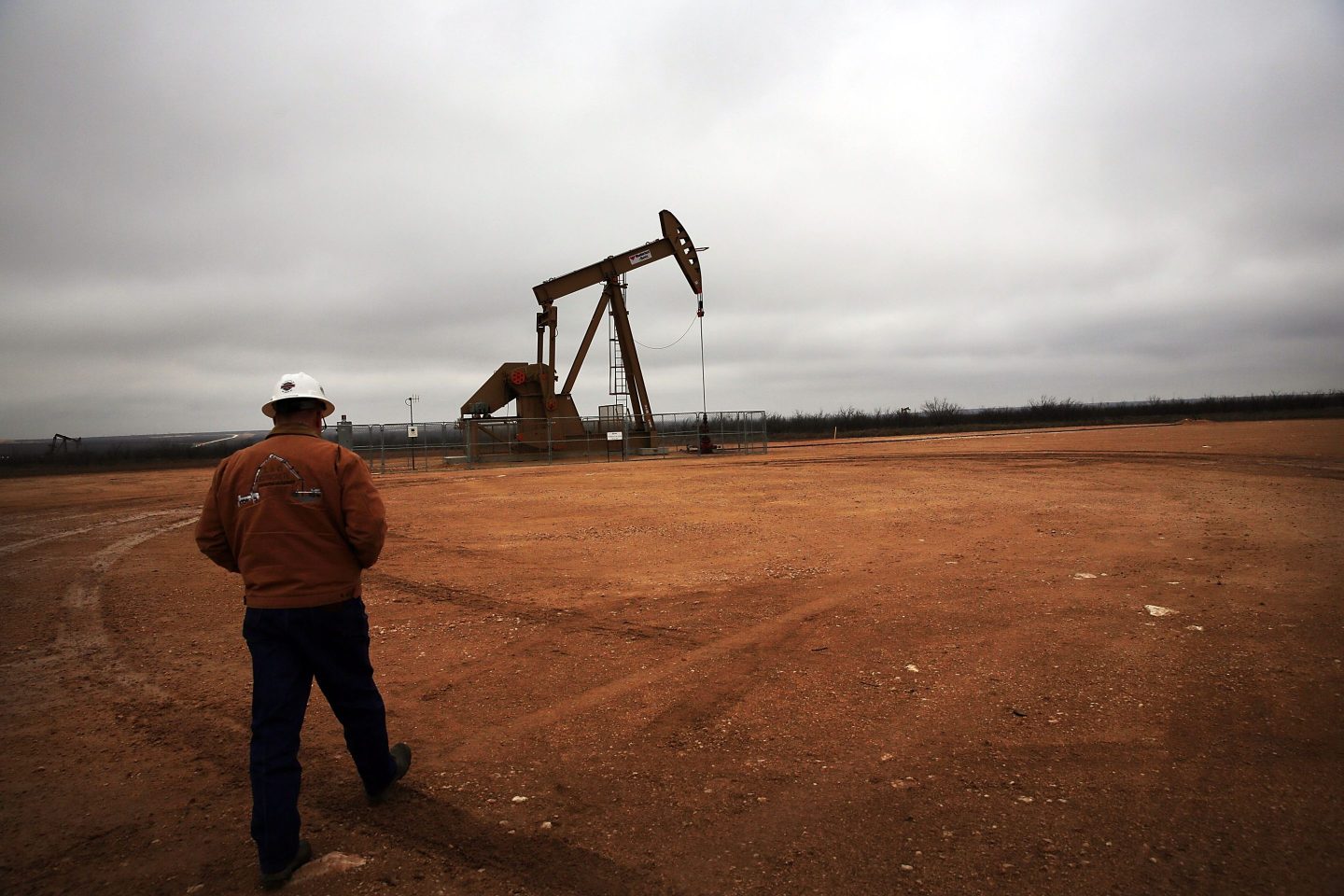 A worker walks toward an oil pump in Garden City, Texas.