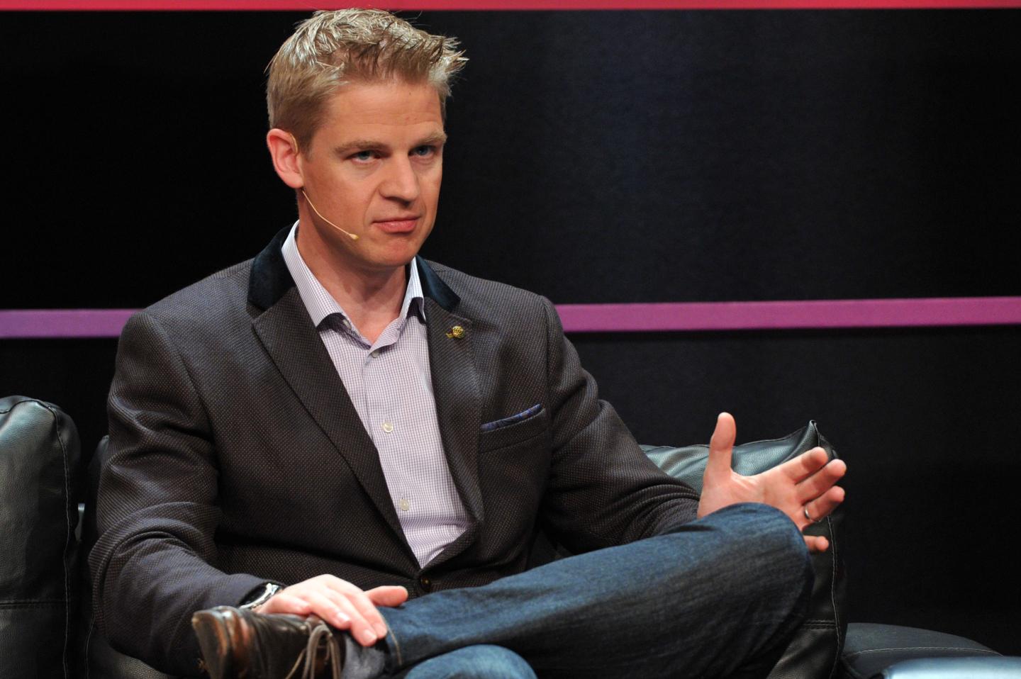 young man wearing a suit jacket seated onstage
