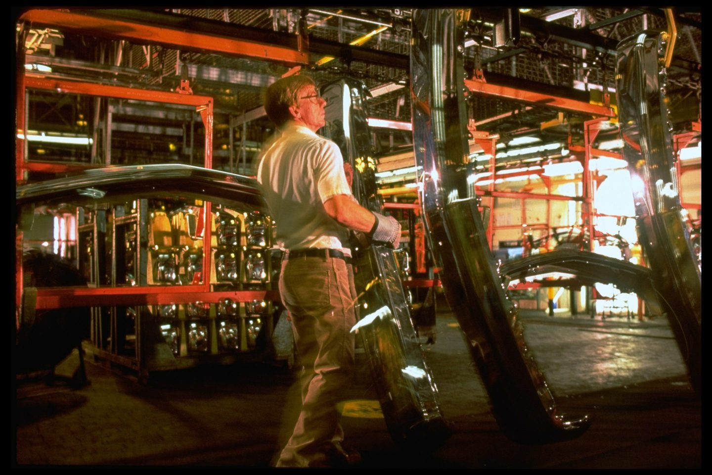 A man stands between machines in a car factory.