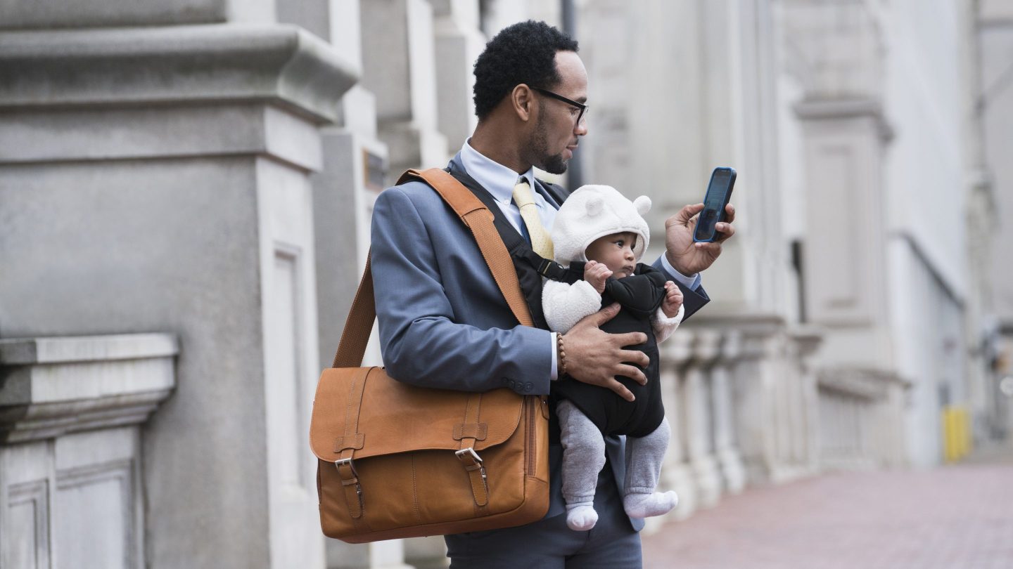 A dad working while holding a baby carrier
