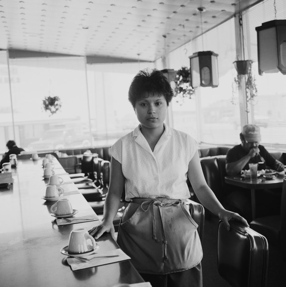 A waitress at a diner sets up seats.