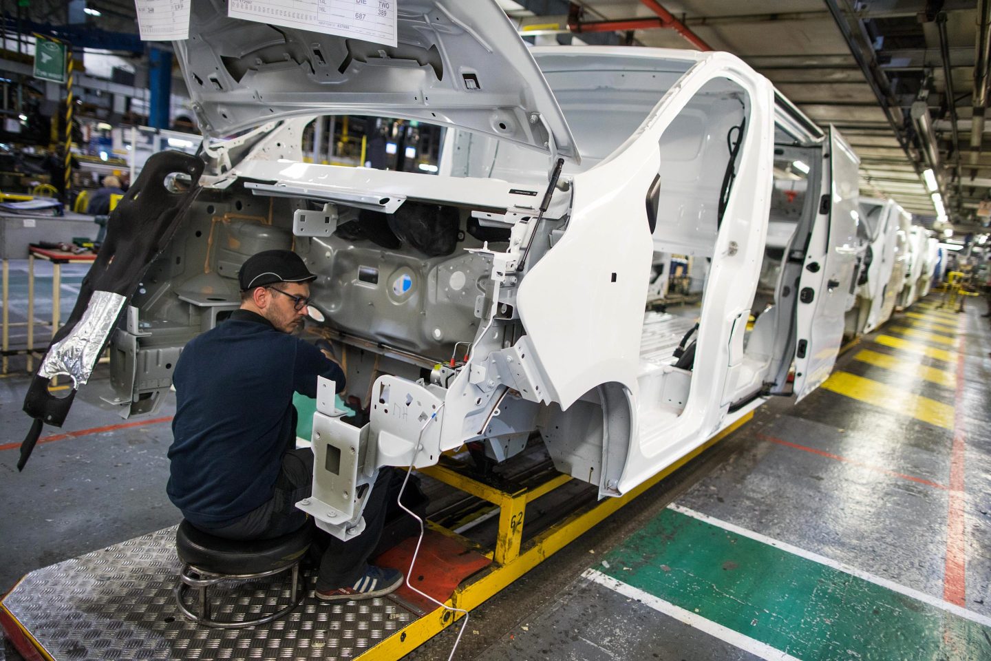 An employee works on the engine compartment of a Vauxhall Vivaro medium sized van on the final assembly line at the Vauxhall plant in Luton, U.K., on Tuesday, April 17, 2018.