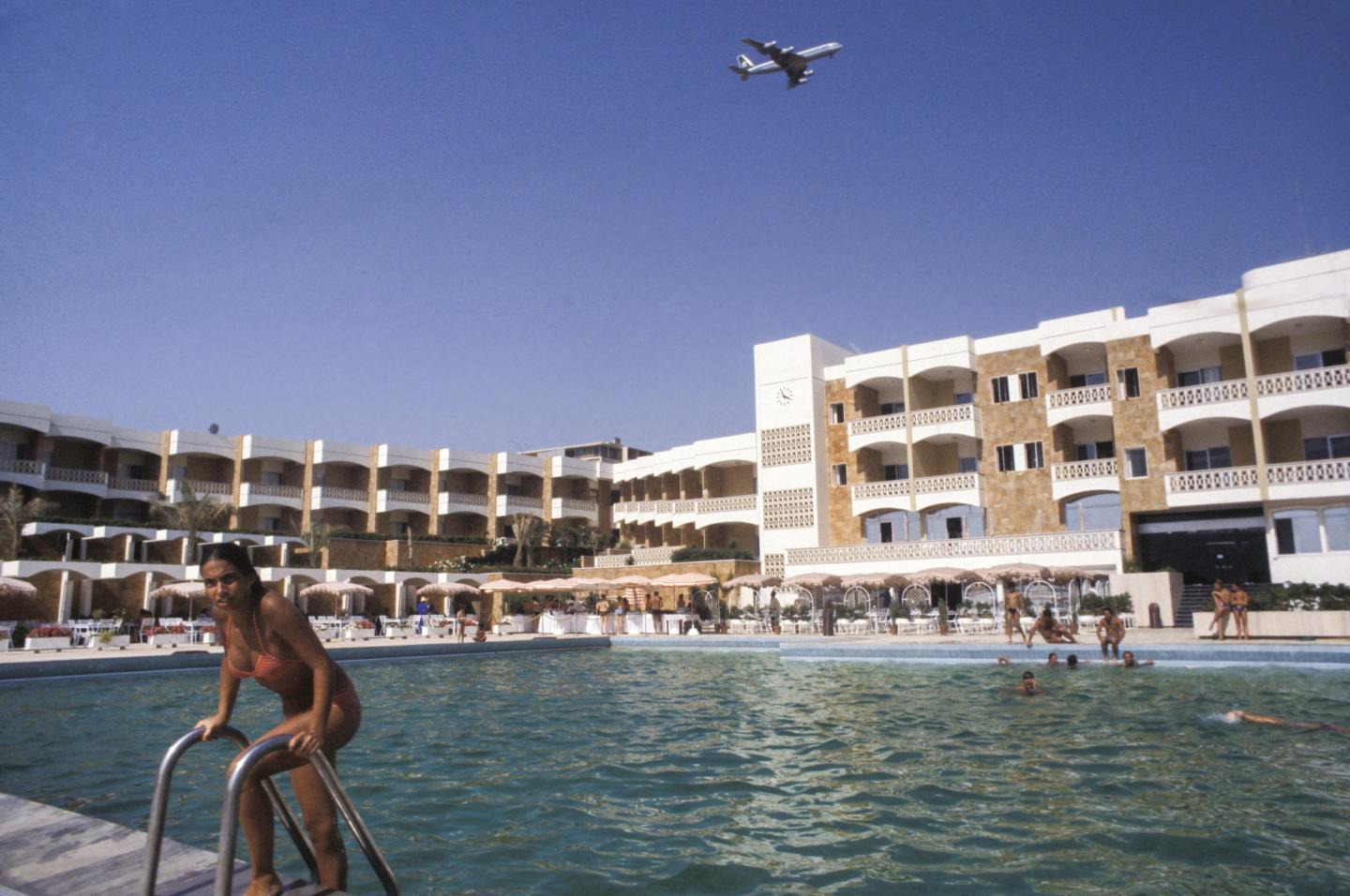 A plane flies over a hotel pool in Beirut