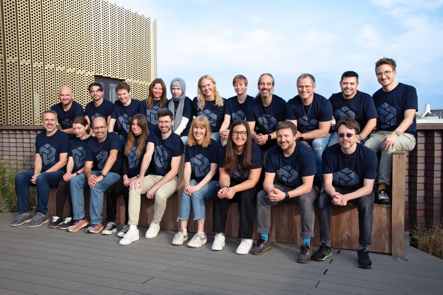Picture of the team at Tessl sitting in two rows on a roof deck all wearing matching blue T-shirts with the company logo.