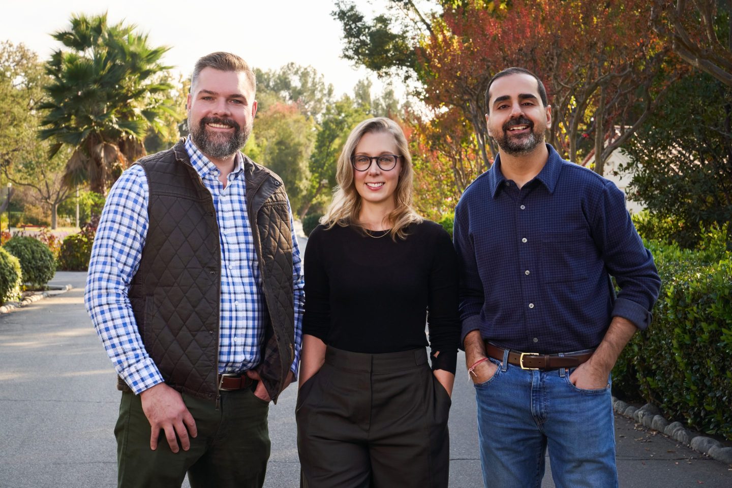 two adult men and one adult woman in business casual clothing pose for a photo