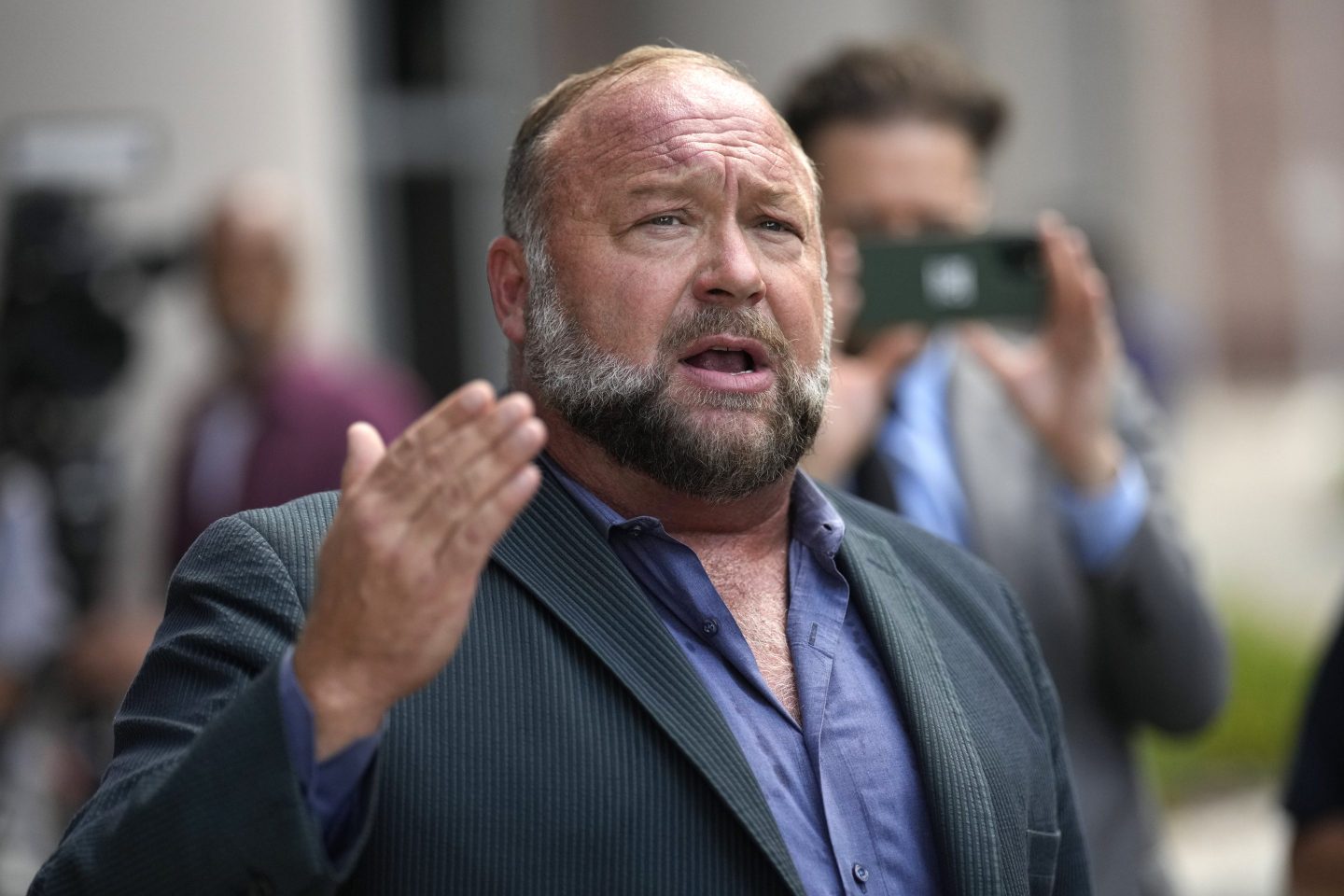 Alex Jones speaks to the media after arriving at the federal courthouse for a hearing in front of a bankruptcy judge, June 14, 2024, in Houston.