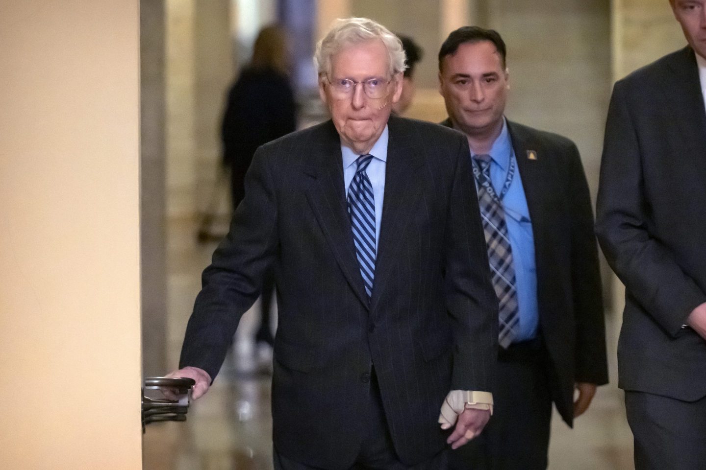Senate Minority Leader Mitch McConnell of Ky., left, wears a bandage on his face and wrist as he walks to cast a vote on the Senate floor after falling during a luncheon on Capitol Hill, on Dec. 10, 2024, in Washington.