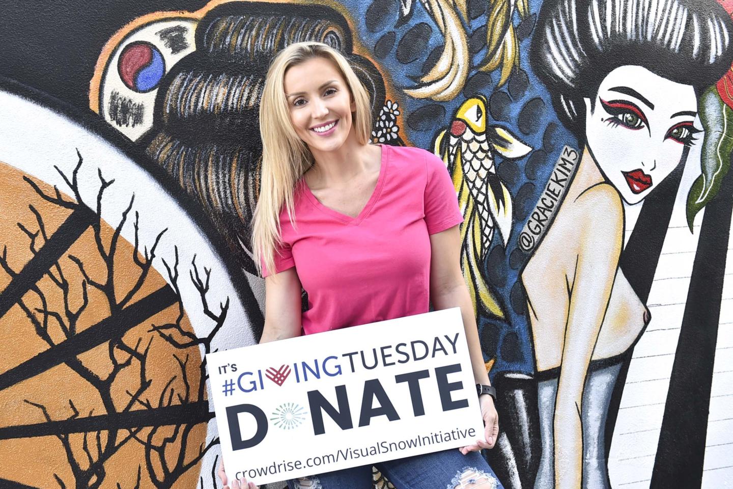 A woman holds a sign saying "Donate" on Giving Tuesday, the first Tuesday after Thanksgiving