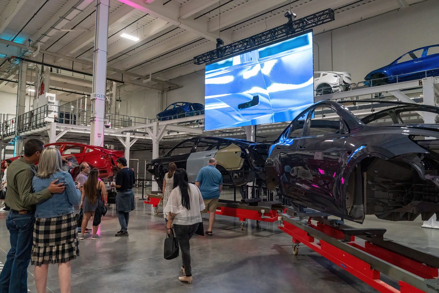 People look at car frames as they tour Tesla's "gigafactory" in Austin, Texas.
