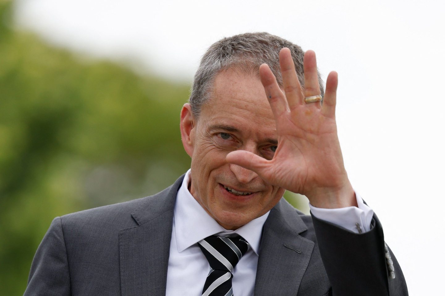 Pat Gelsinger, dressed in a suit, waves at the camera.