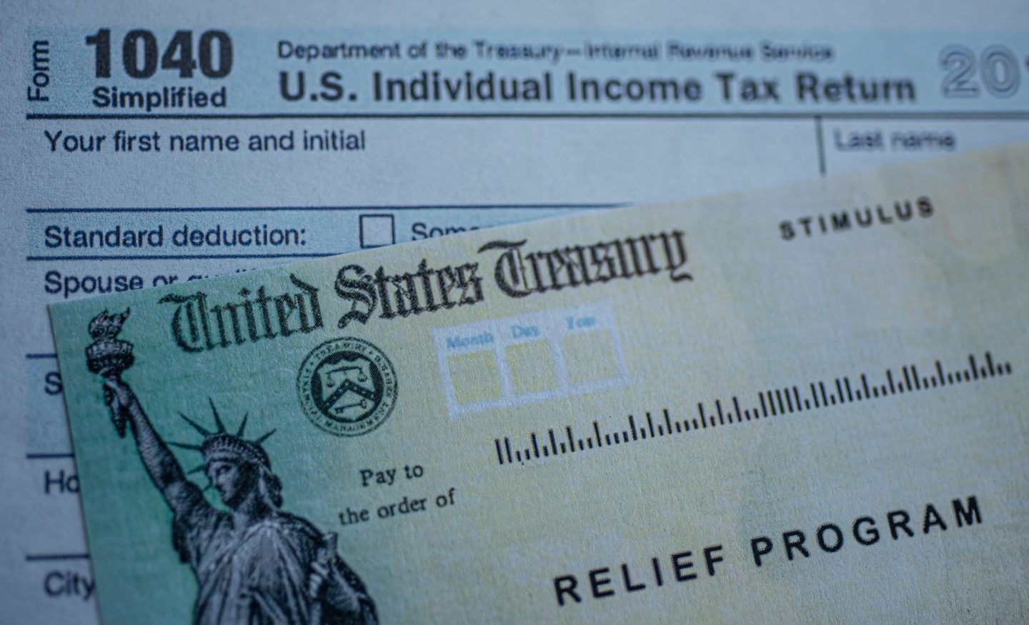 Form 1040 U.S. individual income tax return next to the Stimulus Check Relief program