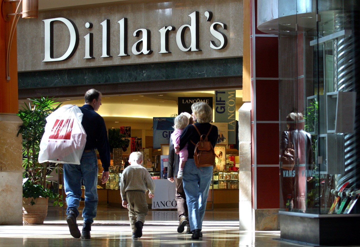 A man, woman, and two children walking into a store called Dillard's.