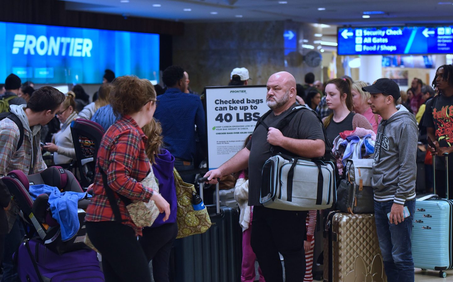 A group of travelers waiting in line at an airport gate.