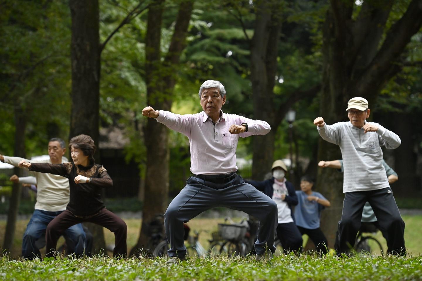 Elderly people perform health physical exercise in a park
