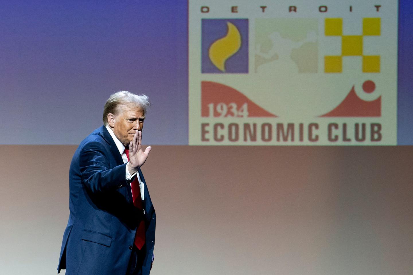 Donald Trump waves to a crowd in an auditorium