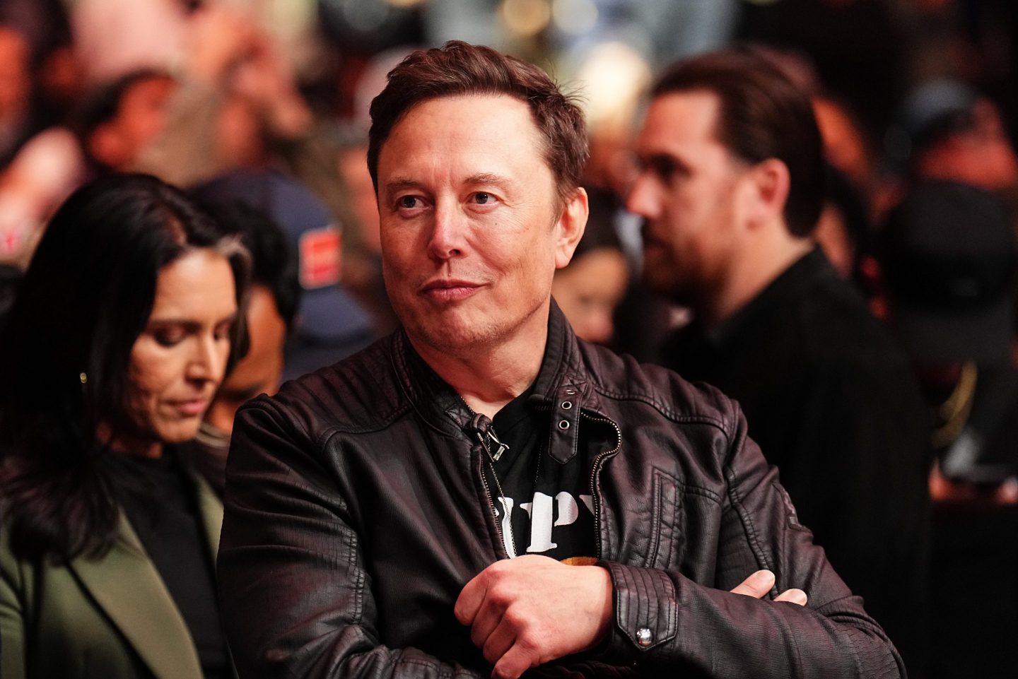 Elon Musk folds his arms while ringside at a UFC event