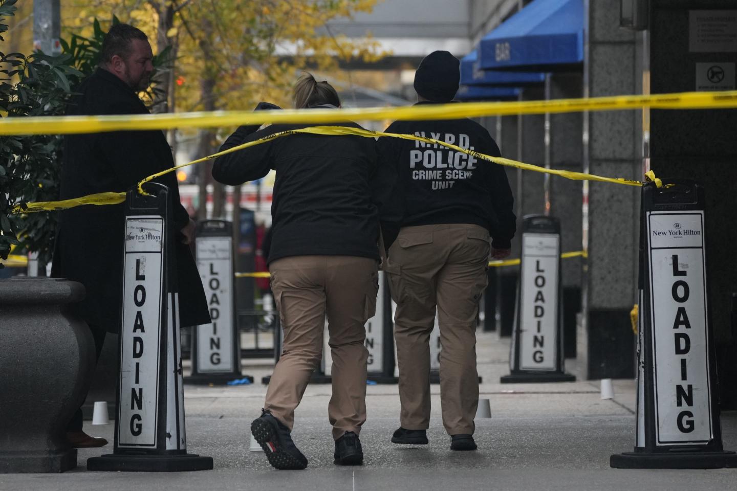 Police cover evidence with paper cups as as CEO of UnitedHealthcare Brian Thompson, 50, was shot as he entered the New York Hilton.