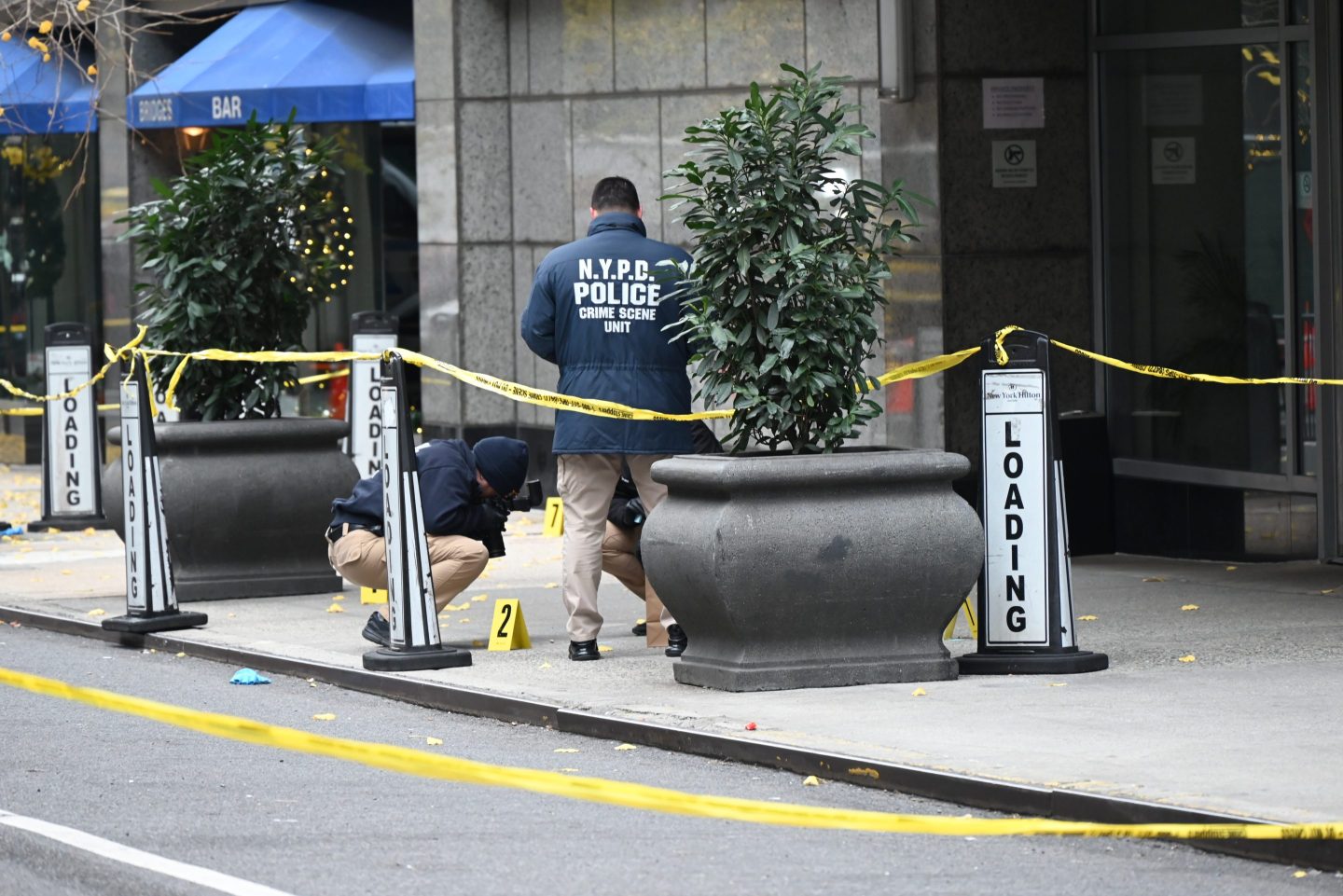 NEW YORK, UNITED STATES - DECEMBER 4: Police officers investigate the scene where UnitedHealthcare CEO Brian Thompson was fatally shot in Midtown Manhattan near a hotel on 54th Street between 6th and 7th Avenues on December 04, 2024 in New York, United States. UnitedHealthcare CEO Brian Thompson, 50, was fatally shot in what authorities are calling a 'brazen, targeted attack' outside the Hilton Hotel in Midtown Manhattan. The masked gunman, who waited several minutes before ambushing Thompson, fired multiple times, striking him in the back and right calf. Thompson was rushed to Roosevelt Hospital but succumbed to his injuries. The suspect fled the scene and remains at large. A $10,000 reward has been offered for information leading to his arrest. (Photo by Kyle Mazza/Anadolu via Getty Images)