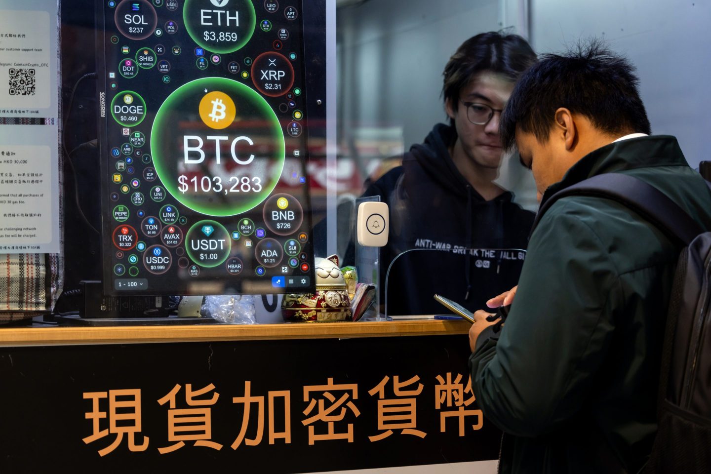 A man has his head down at a cryptocurrency exchange store booth in Hong Kong, China.
