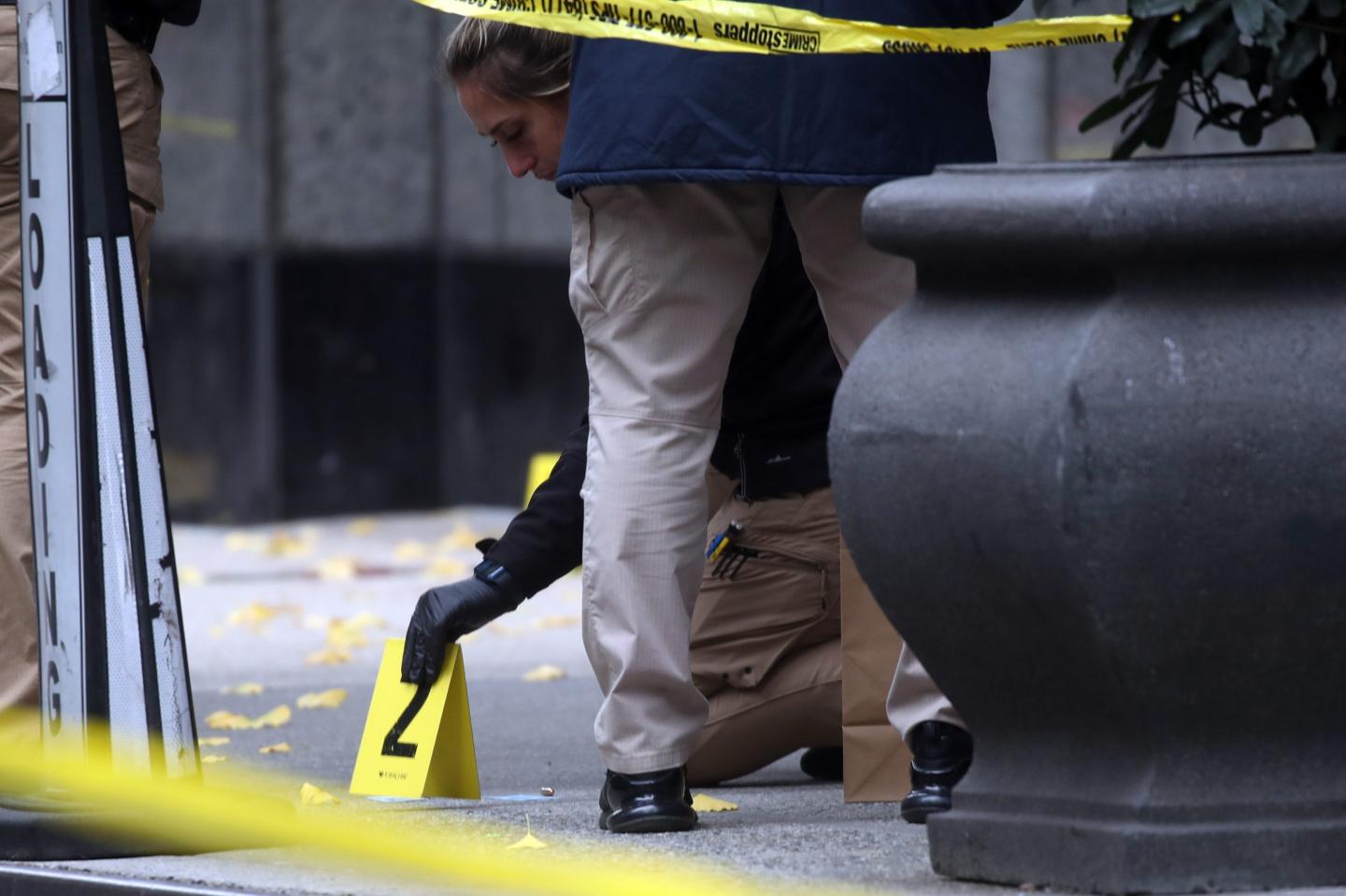 A police officer kneeling at the crime scene of the shooting of UnitedHealthcare CEO Brian Thompson