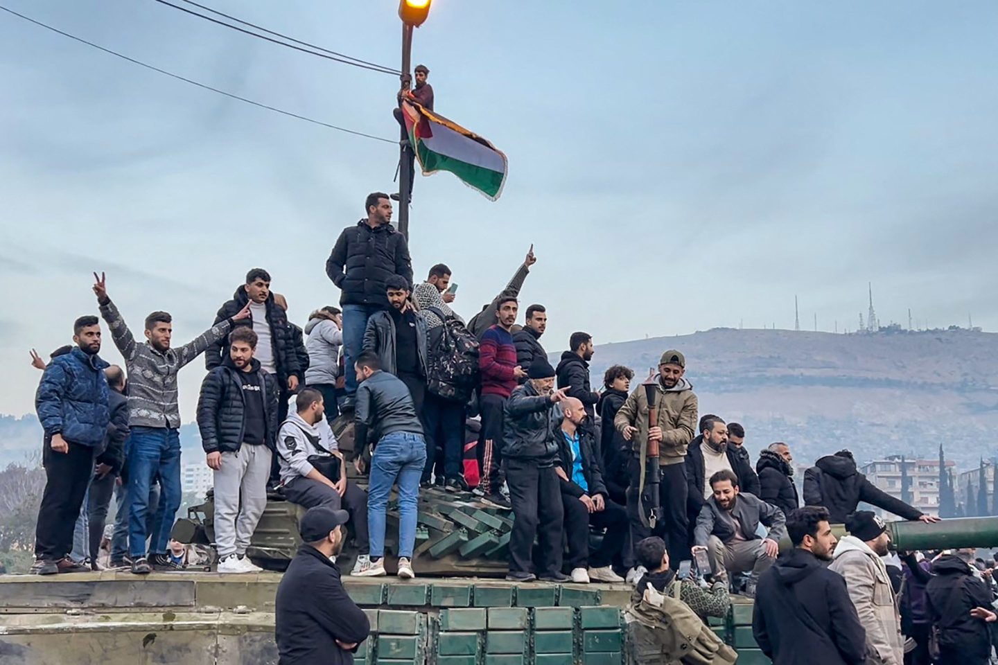 People sitting on a tank as they gather at Umayyad Square in Damascus on Sunday.