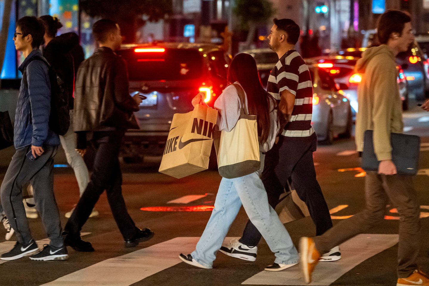 A shopper carries a Nike bag while crossing Geary Street in San Francisco