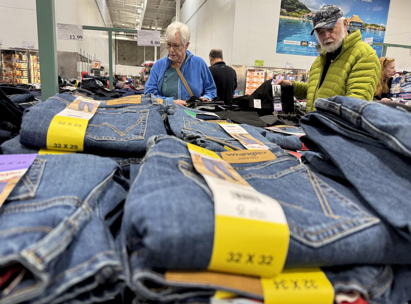Costco shoppers looking over piles of jeans.
