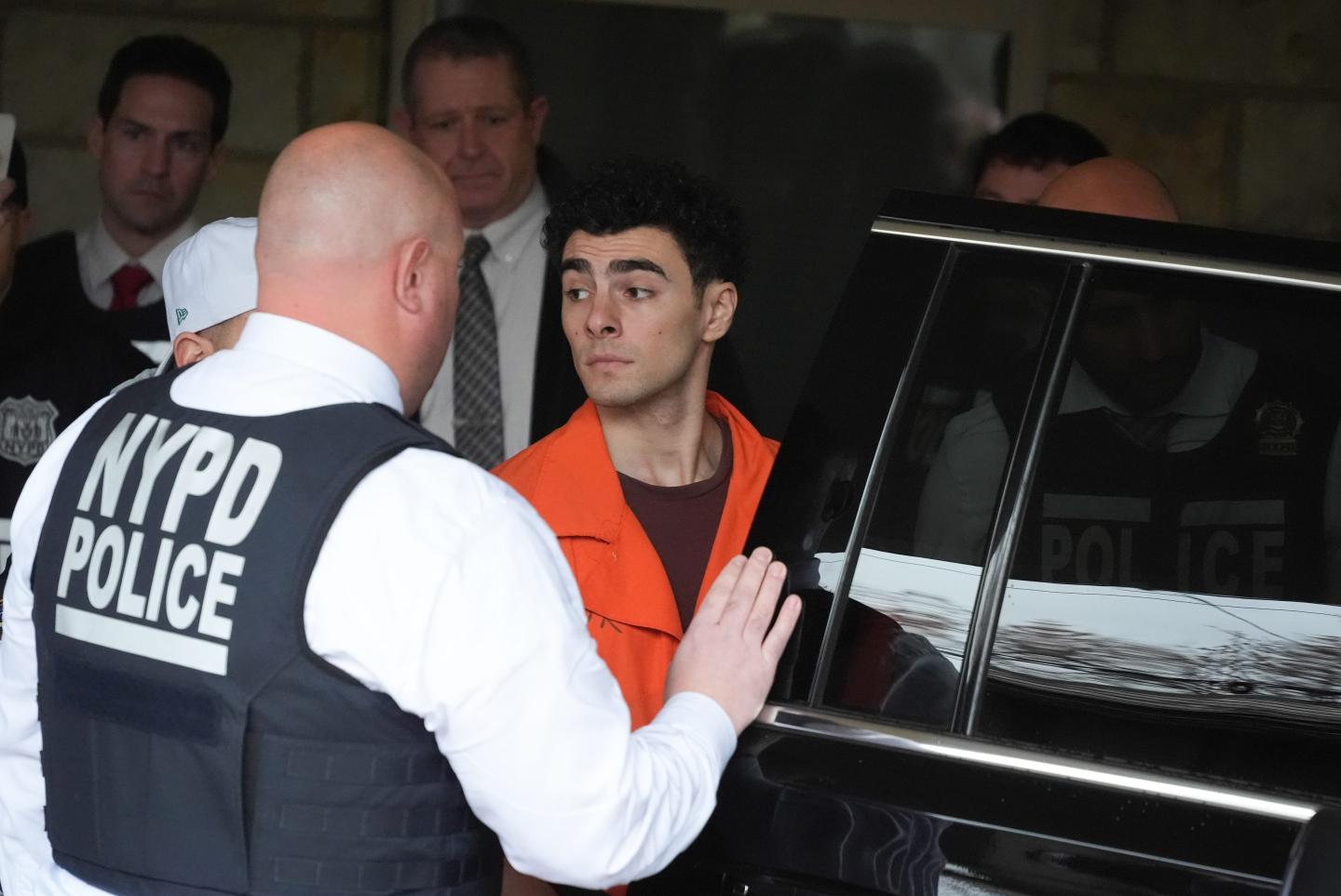 Luigi Mangione gets helped into a police car after his hearing in Pennsylvania