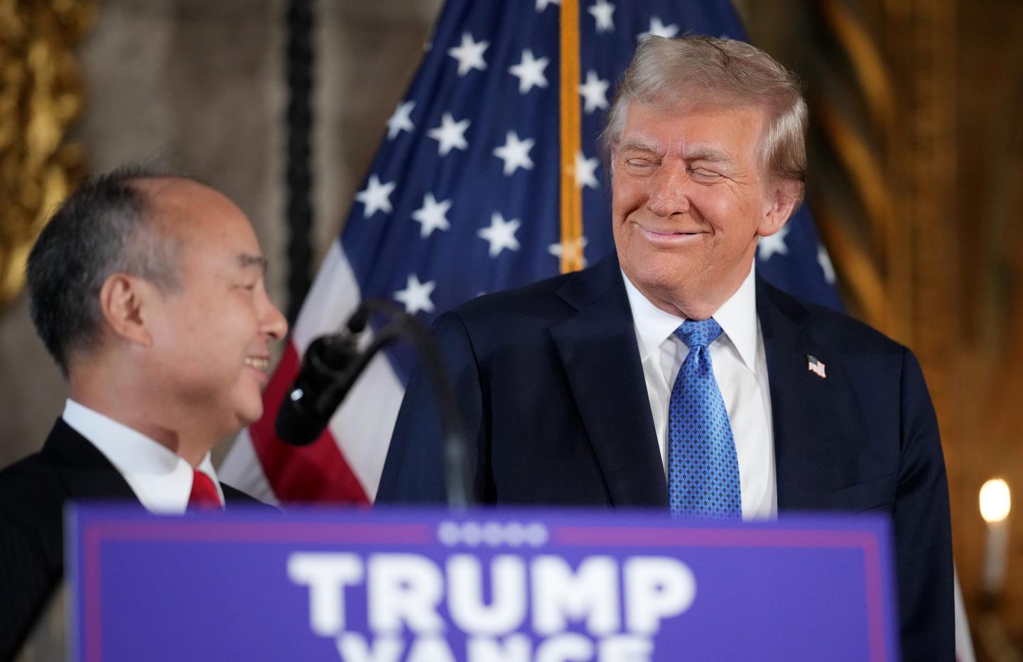 President-elect Donald Trump looks on as SoftBank CEO Masayoshi Son delivers remarks