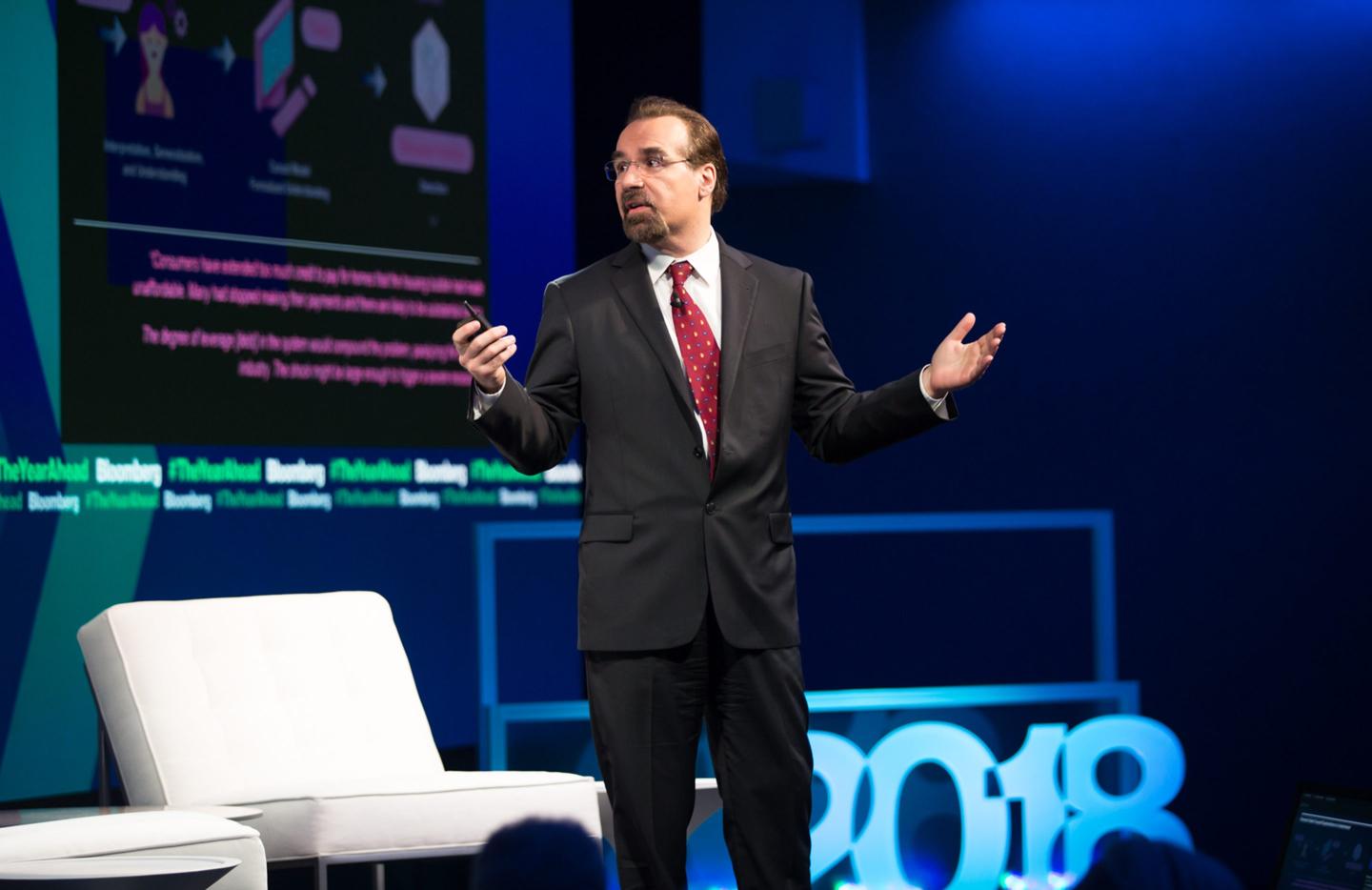 Elemental Cognition founder David Ferrucci speaking on stage at a tech conference.