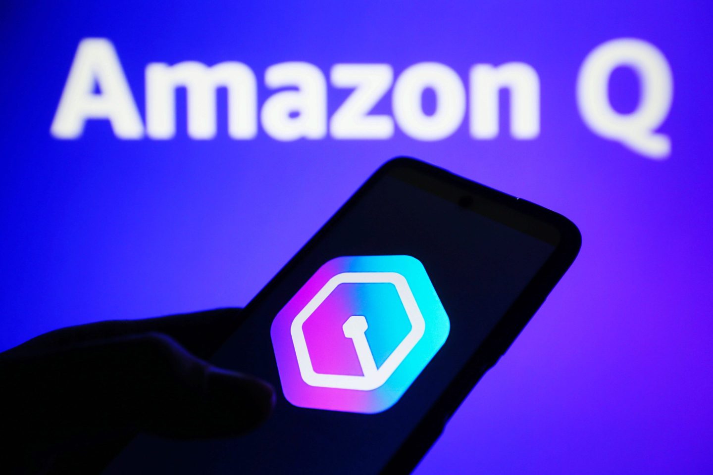 a photo of a hand in the shadows holding a phone with the Amazon Q logo on it, backlit by the words Amazon Q