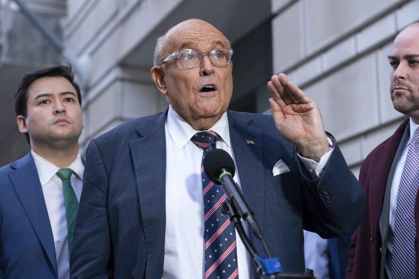 Rudy Giuliani gesticulates in front of reporters outside a courthouse