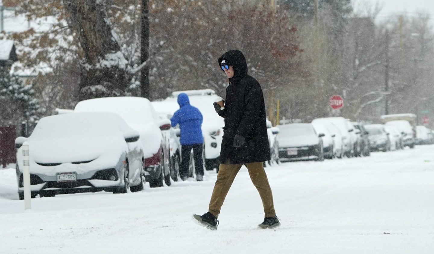 A pedestrian crosses First Avenue as a winter storm sweeps over the intermountain West, plunging temperatures into the single digits and bringing along a light snow in its wake on Jan. 18, 2025, in Denver.