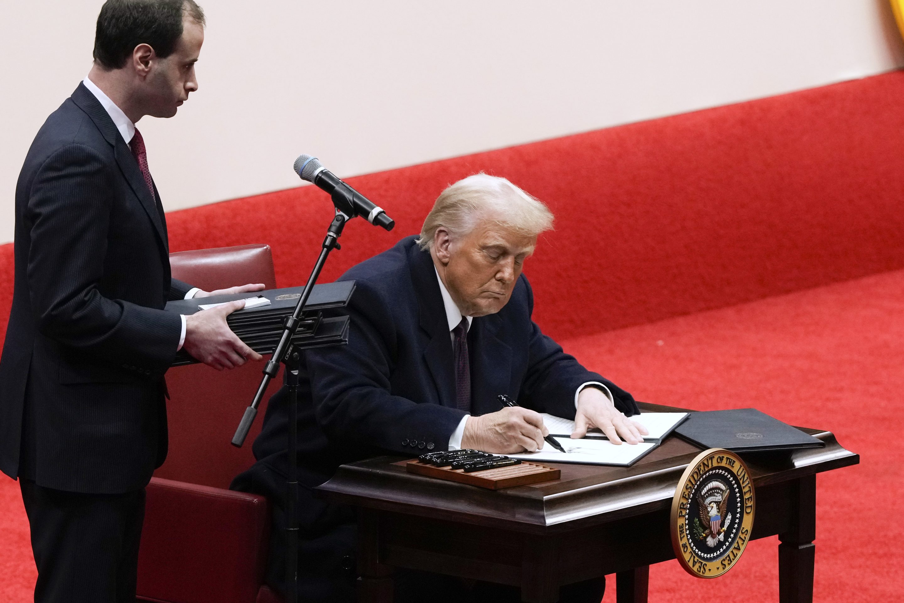 Will Scharf assists as President Donald Trump signs an executive order at an indoor Presidential Inauguration parade event in Washington, on Jan. 20, 2025. 