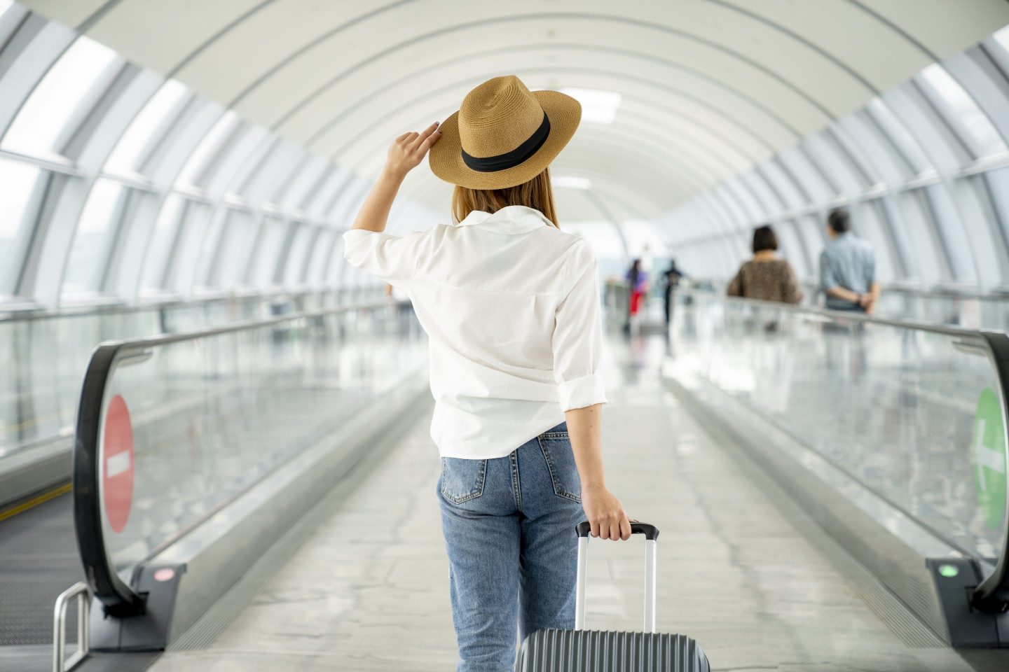 Young casual female traveler with suitcase at airport.