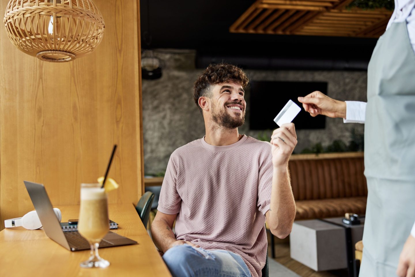 Happy man paying the bill in a café with a credit card..