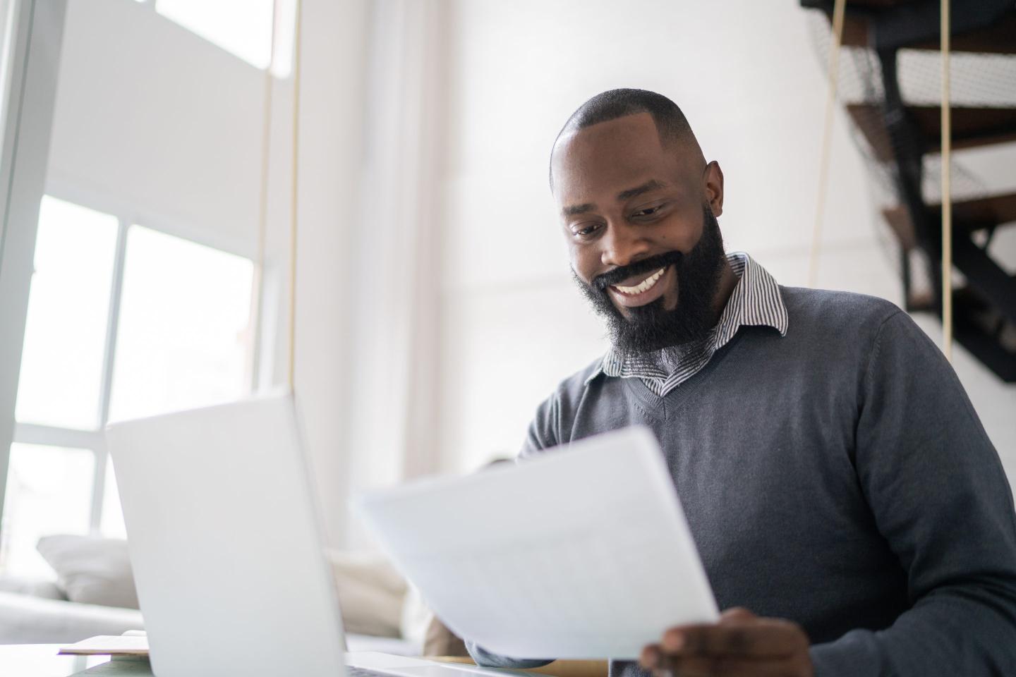 Mid adult man doing home finances using laptop at home.