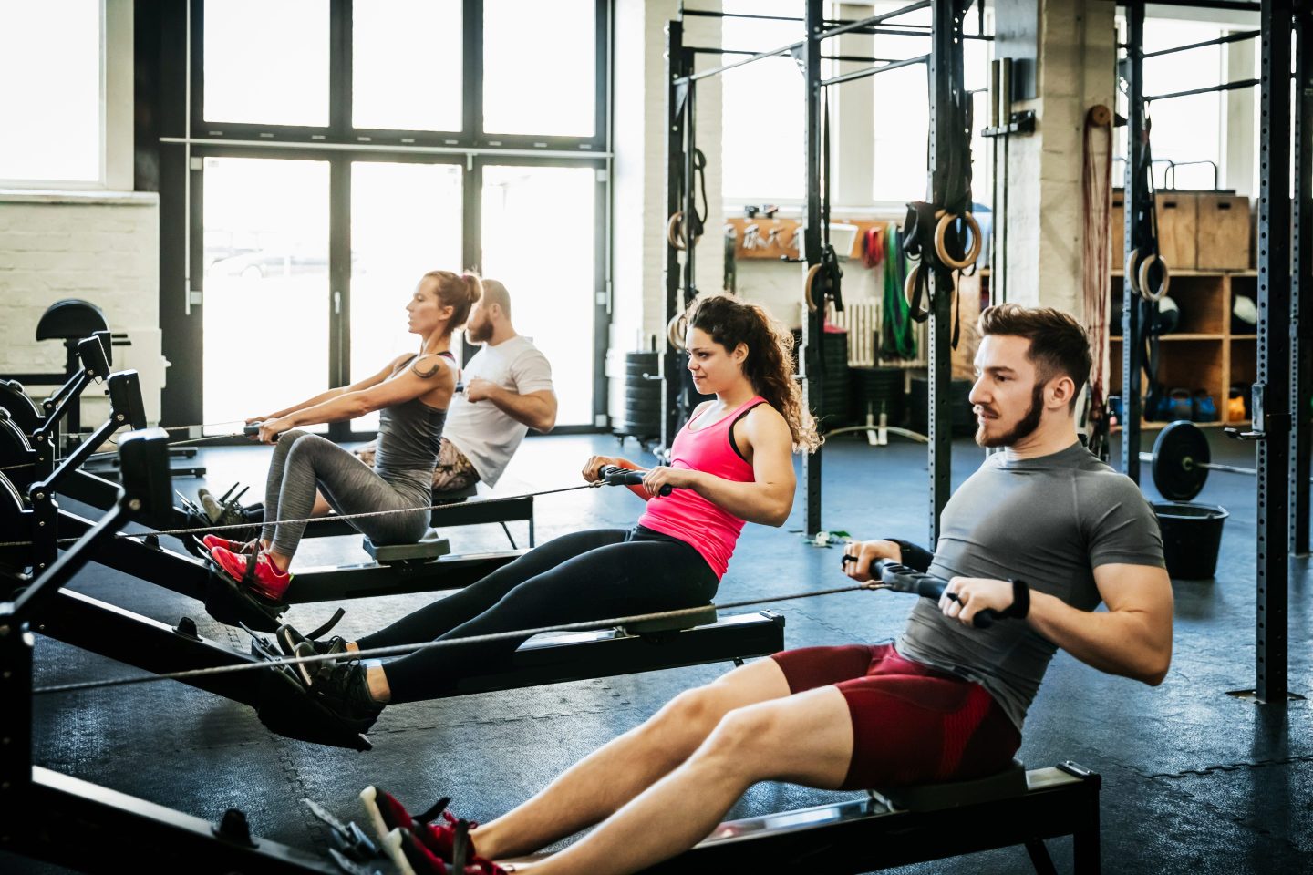 Fitness Enthusiasts Exercising Using Rowing Machines.